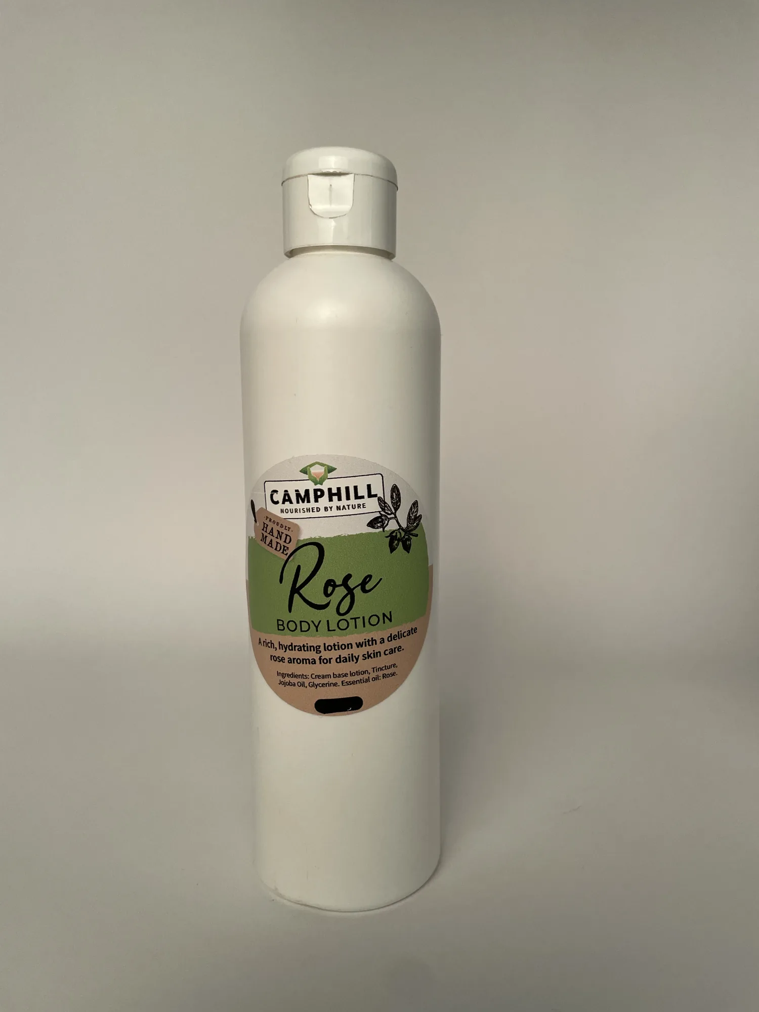 A white bottle of Camphill Rose Body Lotion, described on the label as a rich hydrating lotion with a delicate rose aroma